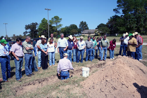 group of people looking at a man in soil pit